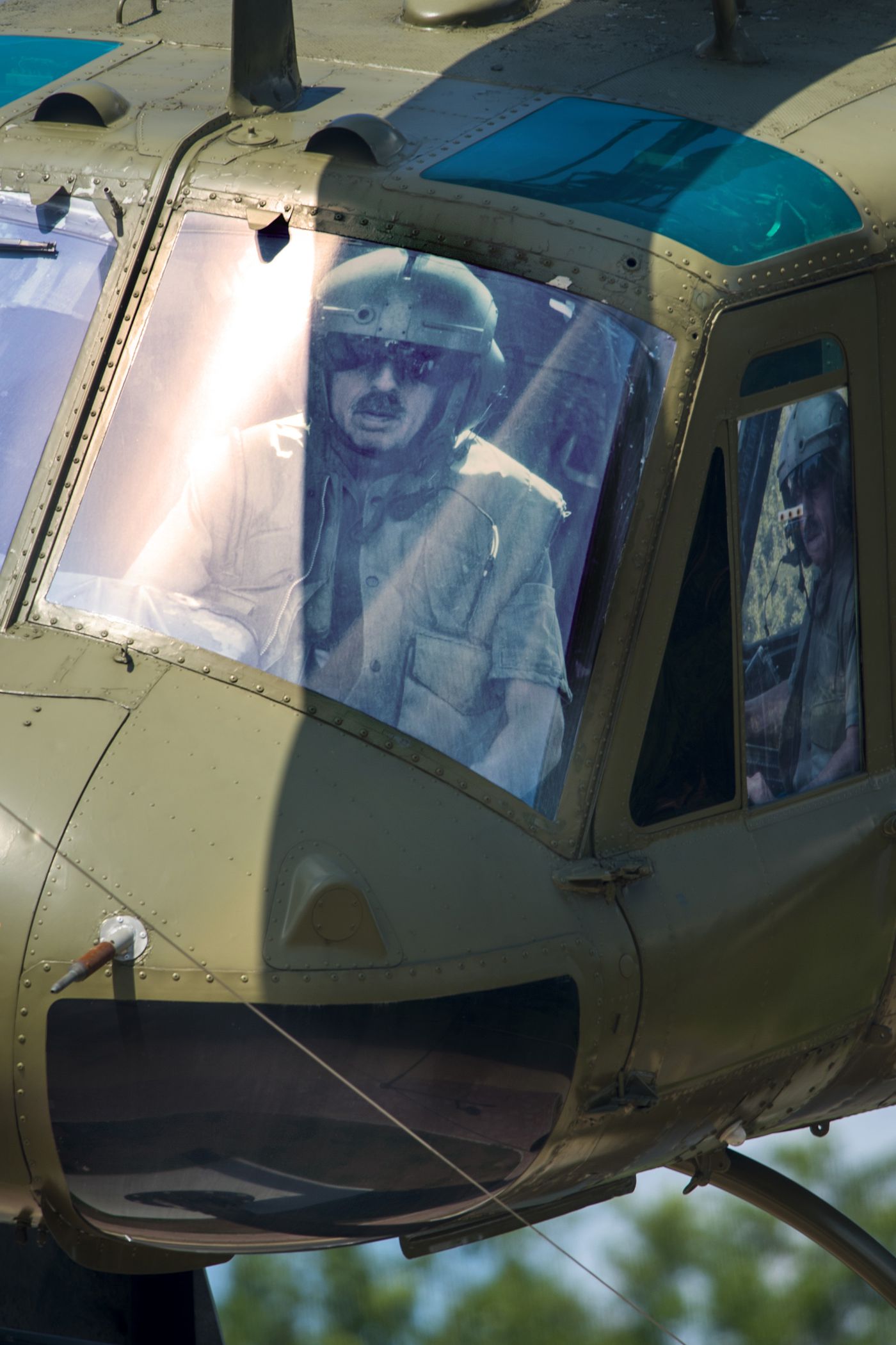 A life-size contemporary photograph of Ralph Storti is in the cockpit of the Huey helicopter. Other community members are pictured in other windows of the chopper.
